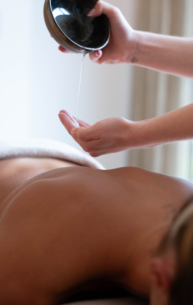 Massage Öl läuft in die Hand für eine Rückenmassage