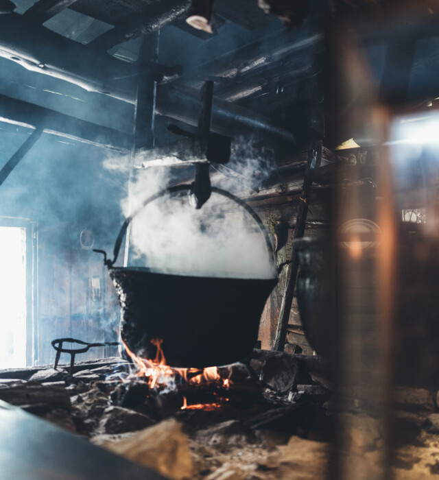 A cauldron over a fire in an old, traditional alpine hut