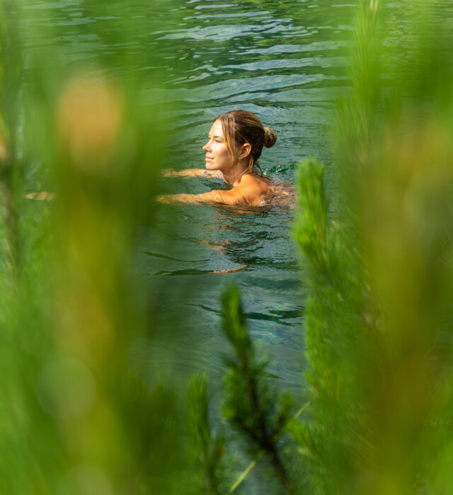 Dame schwimmt im Naturteich umgeben von der Natur