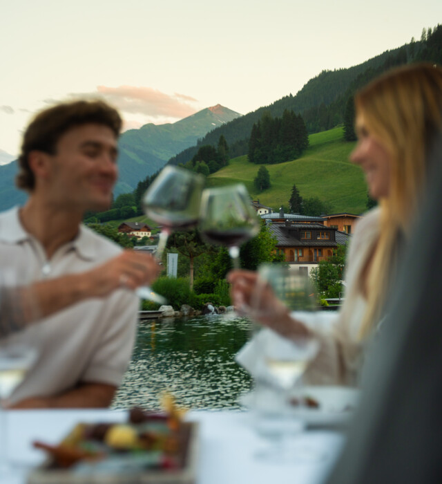 Pärchen beim Dinner stoßen mit einem Glas Rotwein an