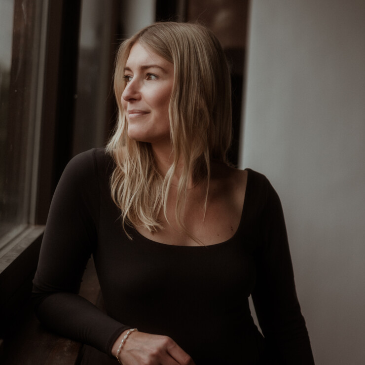 Pilates Trainerin Portrait mit Mokka farbigen Hintergrund