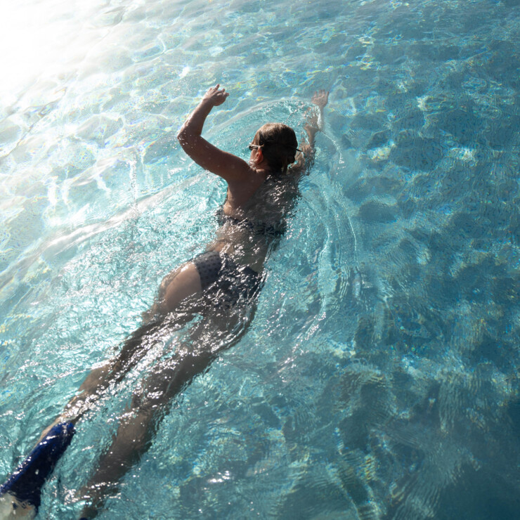 Dame bereitet sich für Längenschwimmen vor mit pinker Badehaube und Brille