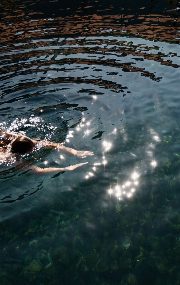 Abkühlung im Naturbadeteich. Eine Dame schwimmt.
