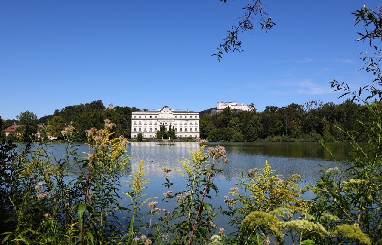 A view of Leopoldskron Castle against a blue sky and green countryside