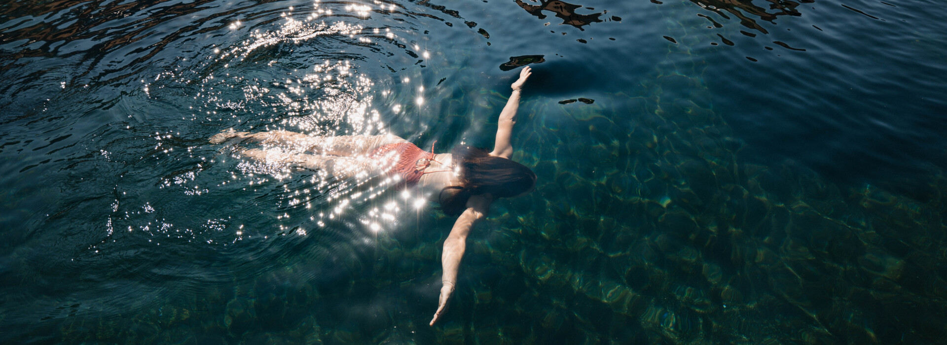 Außenpool mit großzügigen Holzliegen im Wasser im Wellnesshotel Nesslerhof, Großarl.